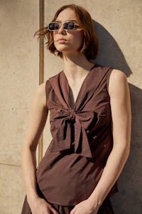 a woman wearing sunglasses and a brown top