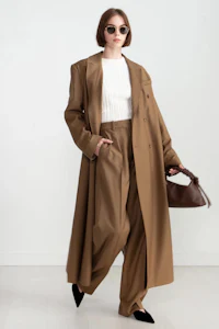 a woman wearing a camel coat and white shirt