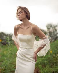 a woman in a white wedding dress standing in a field