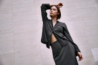 a woman is posing for a photo in a grey shirt and skirt